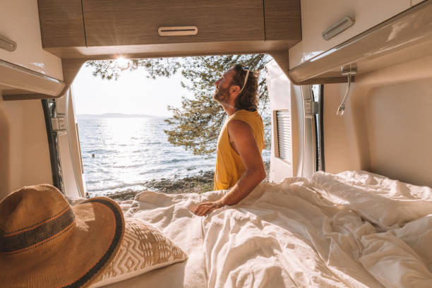 istock Man lying in a van looking at ocean 1350675726