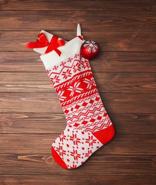istock Christmas stocking white with a red pattern with gifts hanging on a wooden wall. 1350682874