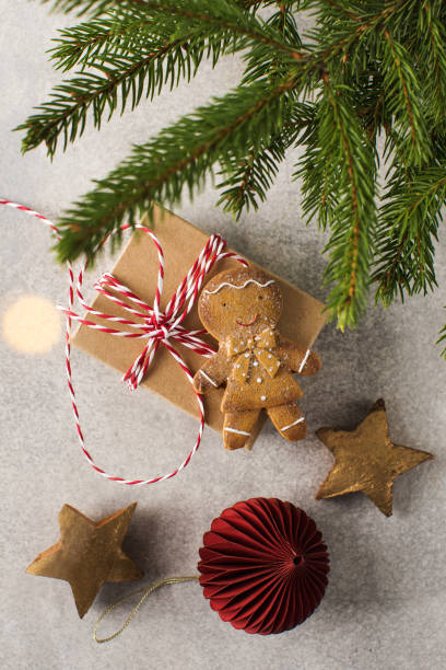 istock Presents and gingerbread man lie on grey background with Christmas tree branches 1350683480
