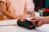 Close-up view of unrecognizable male customer paying with NFC technology by credit card contactless on POS terminal, selective focus.