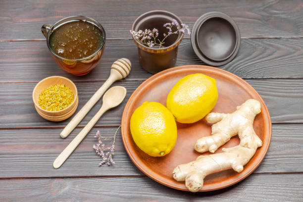 два целых лимона и корень имбиря на керамической тарелке - grater grated peel ingredient стоковые фото и изображения