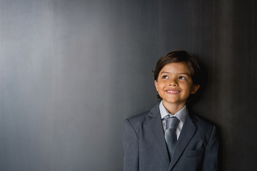 Portrait of a thoughtful Latin American boy thinking as business man and smiling