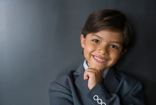 Portrait of a happy Latin American boy pretending to be a successful business man and looking at the camera smiling