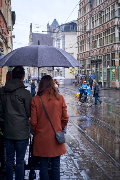 Ghent, Belgium - October 30, 2021: People walk outdoors on a rainy day in Ghent