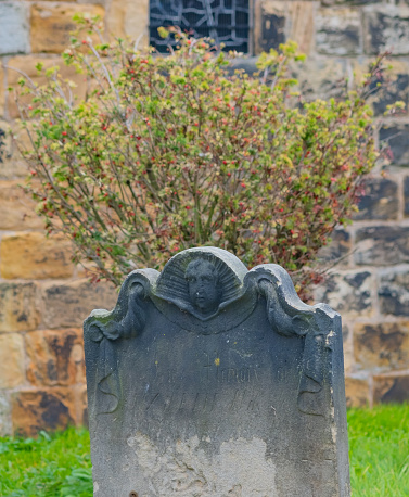 Close and selective focus on a decorative headstone, dating back to the 1800s in a cemetery or church yard