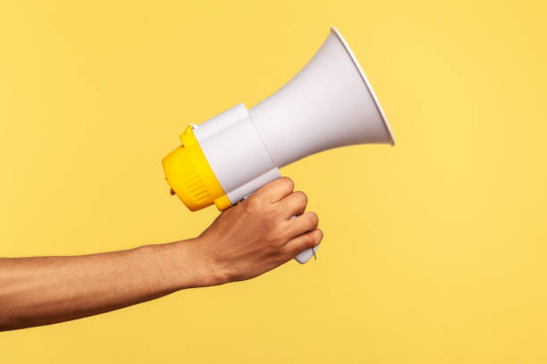 Profile side view closeup of human hand holding megaphone, announcing of advertisement. stock photo