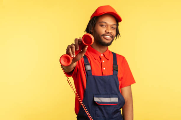 istock Positive handyman holding out handset, asking call him and order service, looking friendly at camera 1350692563