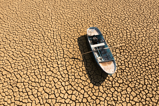 Aerial view of a single fishing boat on the dry surface of a drought lake bed. Taken via drone. Burdur,  Turkey.