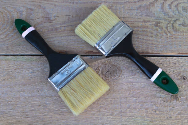 istock Two new paintbrushes on a wooden background - Construction concept 1350695871