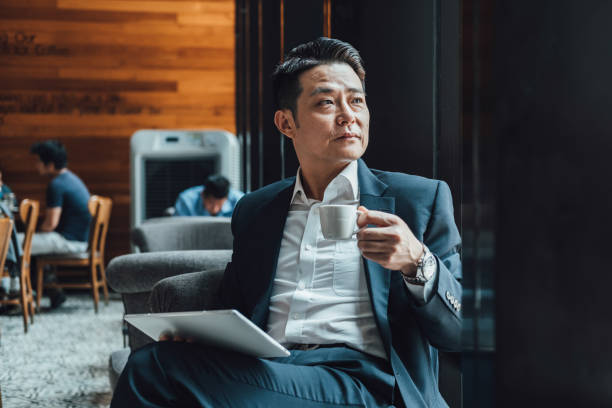istock Handsome Asian Businessman Using Digital Tablet in a Cafe 1350699865