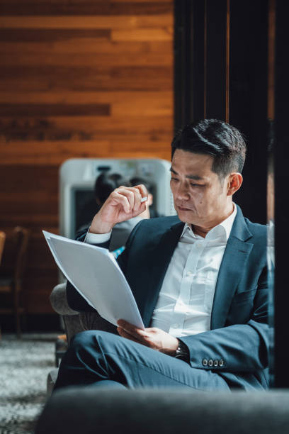 istock Handsome Asian Businessman Reading Documents in a Cafe 1350699869