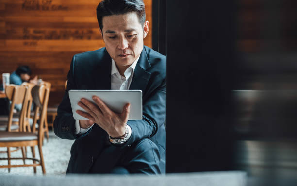 istock Handsome Asian Businessman Using Digital Tablet in a Cafe 1350699872