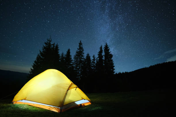 istock Brightly illuminated camping tent glowing on campsite in dark mountains under night stars covered sky. Active lifestyle and traveling concept. 1350700672