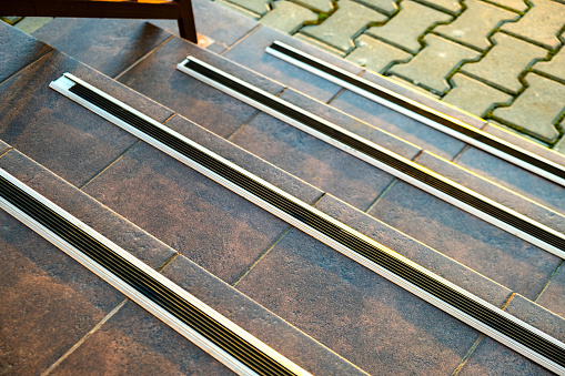 Closeup of ceramic tiles covering porch stairs with rubber anti slippery stripes on it.