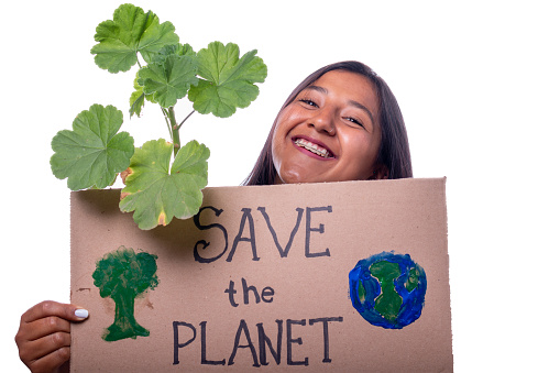 Portrait of latin and brunette woman holding banner saying save the planet, isolated on white background. Smiling woman holding plant and banner with ecological message. Protestant and social activist