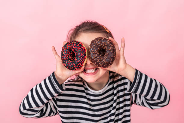 istock Funny little girl with donuts on a pink background. 1350706684