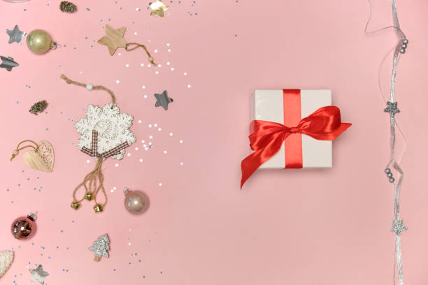istock Christmas gift in white wrapping paper with a red bow. Pink background. 1350706833