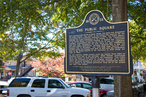 Dahlonega, Georgia - October 26, 2021: A standing marker describes the long history and many traditional uses of the public square, now the center of a thriving commercial district featuring unique shops, hotels, and eateries.