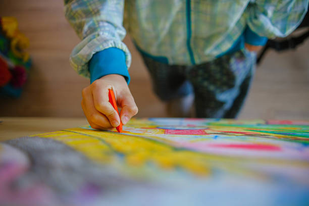 istock Unrecognizable boy drawing with wax colors 1350709115