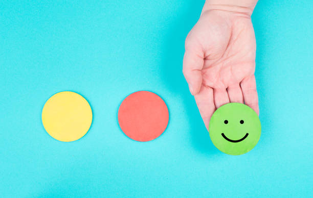 istock Hand holds a green smiling face, red and yellow circle empty, blue colored background, copy space, customer review 1350713472