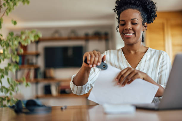 Adult woman, using her new stapler for the first time Happy african-american woman, closely connecting the paper stapled paper stock pictures, royalty-free photos & images