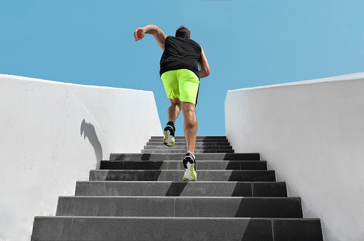 Stairs exercise fitness man running fast up the staircase for hiit cardio workout run at outdoor gym. Sport active athlete lifestyle training legs muscles.