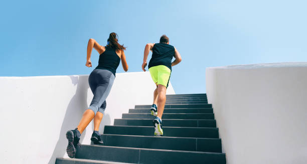 Stairs runners running up staircase training hiit workout. Couple working out legs and cardio at fitness gym. Healthy active lifestyle sport people exercising climbing staircase in urban city stock photo