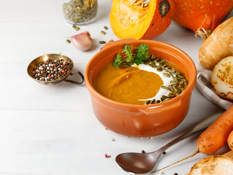 Hot autumn or winter dish, cream soup with baked pumpkin and vegetables. In a ceramic bowl. Close-up.