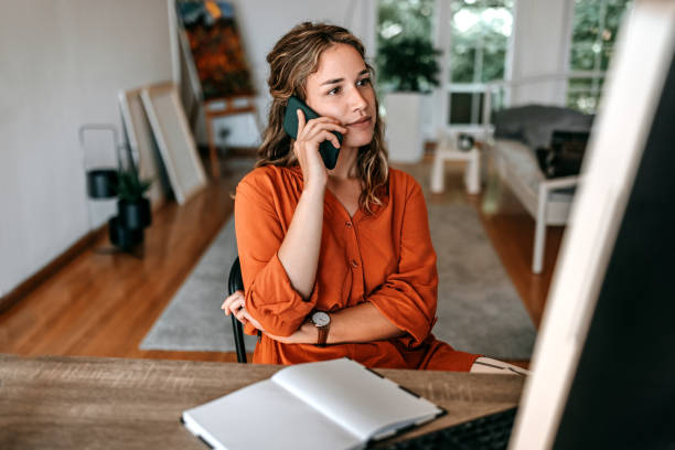 giovane donna che parla al telefono intelligente nell'ufficio di casa - usare il telefono foto e immagini stock