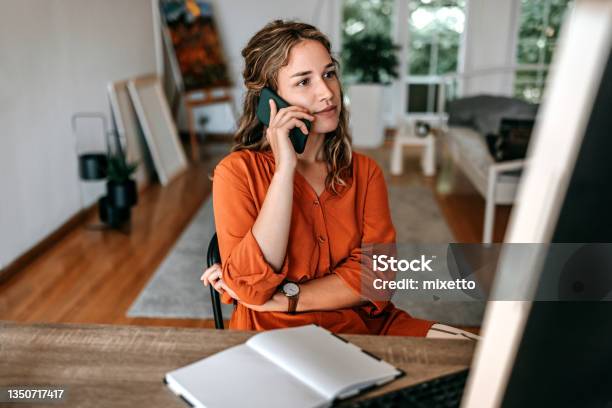 Young Woman Talking On Smart Phone At Home Office Stock Photo - Download Image Now - Using Phone, Women, One Woman Only