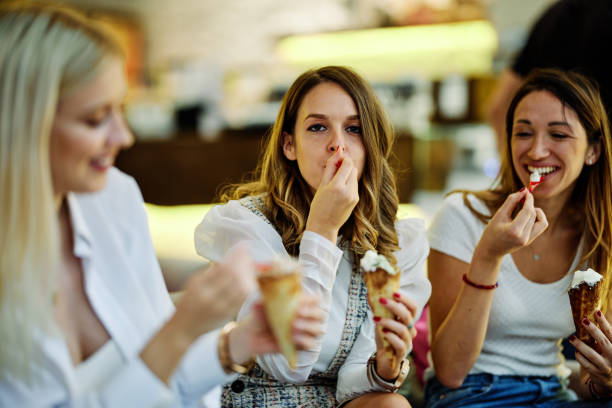 trzy szczęśliwe dziewczyny siedzą w restauracji, rozmawiają i jedzą lody po zakupach. - child laughing blond hair three people zdjęcia i obrazy z banku zdjęć