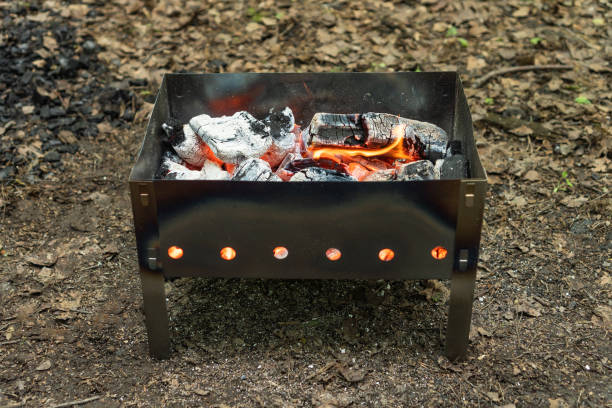 石炭を燃やすキャンプ用の小型軽量ポータブルバーベキューグリル。バーベキューの前に。 - grilled broiling outdoors horizontal ストックフォトと画像