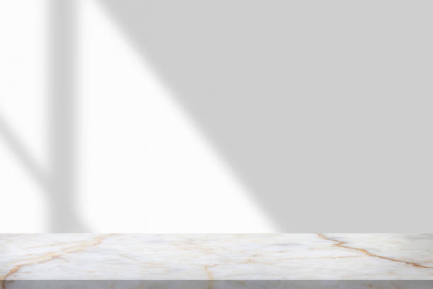 istock Marble table with window shadow drop on white wall background for mockup product display 1350730515