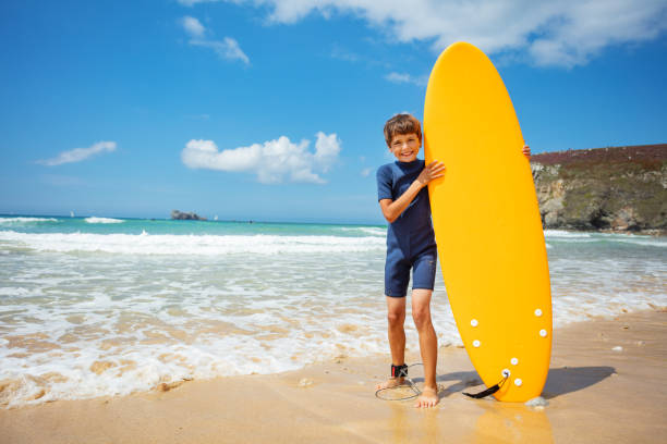 istock Boy pose holding orange surfboard stand in sea 1350731732