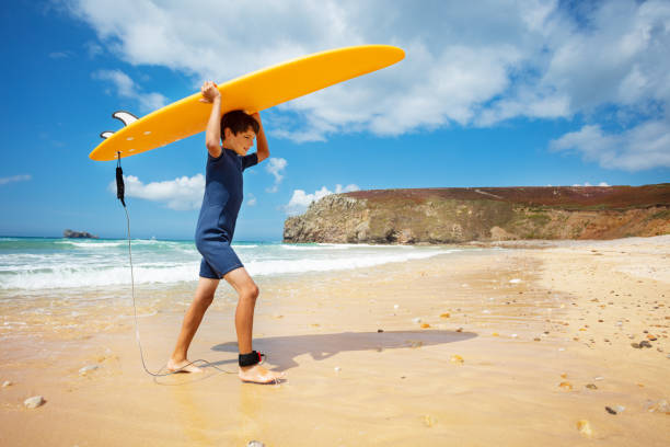 istock Boy with surfboard return from sea to the beach 1350731737