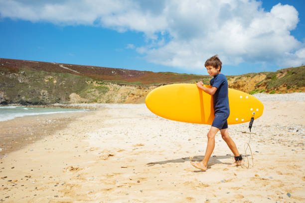istock Boy walk on beach into sea hold surfboard in hands 1350731756