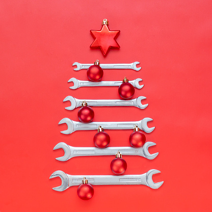 Creative christmas tree on red background, made of wrenches. Industrial greeting card and happy new year concept. Square