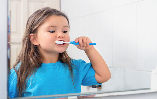 Child girl brushing teeth with a toothbrush in the bathroom