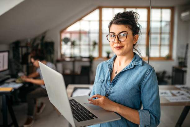 istock Young office worker woman with laptop looking at camera 1350738292