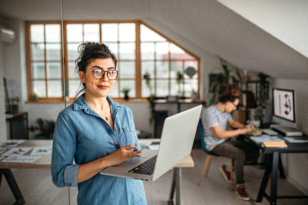 カメラを見てラップトップを持つ若いサラリーマンの女性 - computer businessman businesswoman people ストックフォトと画像