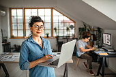 Young office worker woman with laptop looking at camera