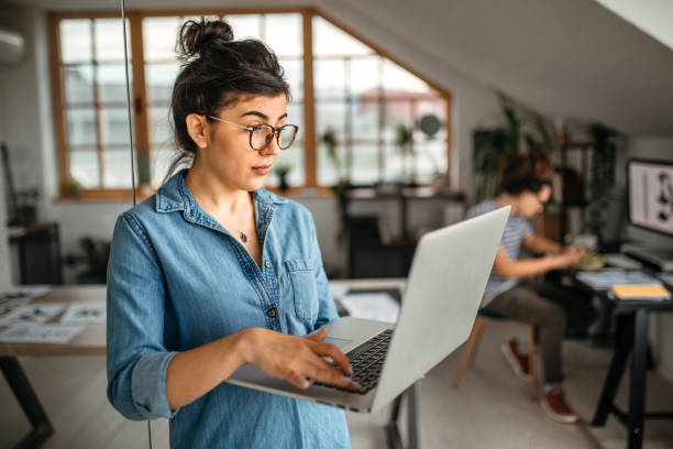 istock Young office worker woman with laptop looking in screen 1350738355
