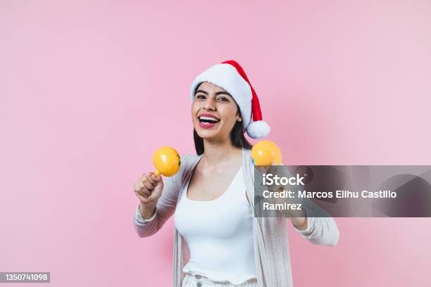 Portrait Of Young Latin Woman Holding Maracas Rattle With Copy Space In A Christmas Concept On Pink Background Stock Photo - Download Image Now