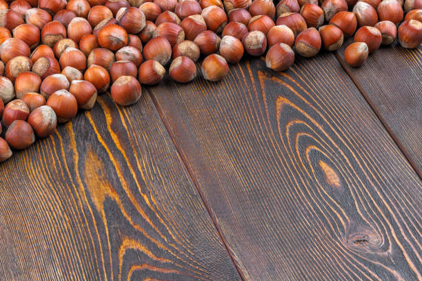 hazelnuts with shells laid on brown wooden table surface with diagonal composition and copy space