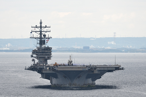 Norfolk, Virginia, USA - May 30, 2023: An American flag waves in the wind on the stern of the USS George H.W. Bush (CVN-77) aircraft supercarrier docked at Naval Station Norfolk while in port.