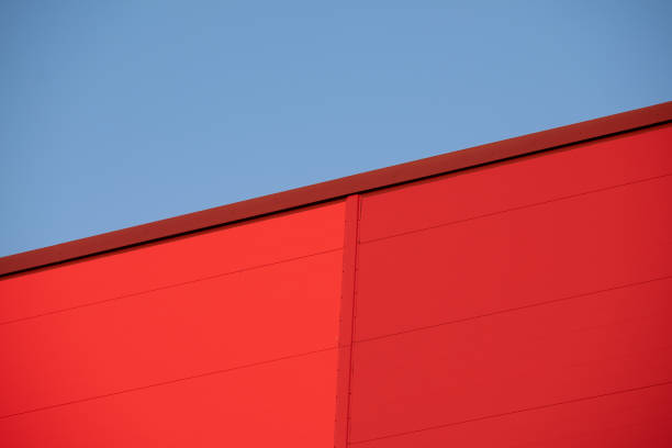 Closeup of red metallic building wall against bright blue sky during the sunset. stock photo