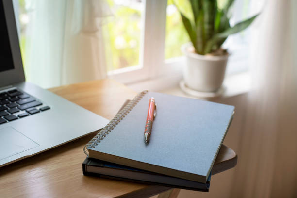 istock Diary and Planner Book on School table for Student, study for exam. Wooden desk with laptop, notebook,  notebook, plant, and pen. Desk for student work at home concept. 1350755331