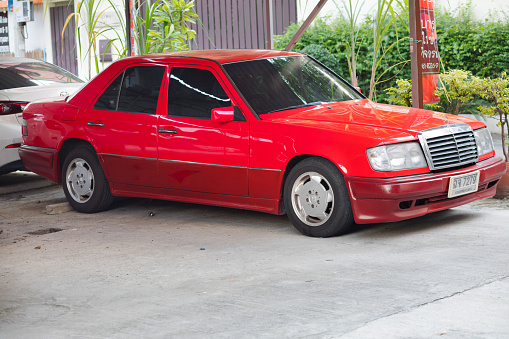 Red Mercedes oldtimer from 1980ies parked on parking lot with other cars in Bangkok