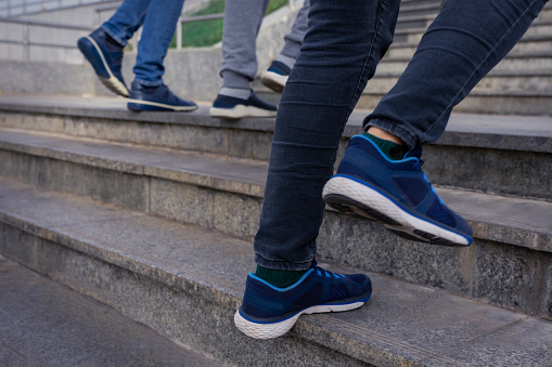 People walking up the stairs. Close up legs in jeans and sport shoes sneakers. Photo with blur in motion.
