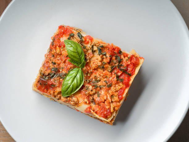 Piece of lasagna on white plate close-up. Menu of Italian cuisine.